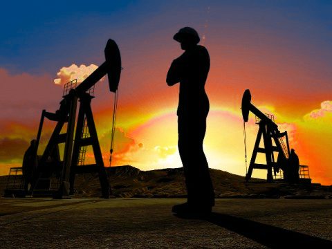Silueta de un trabajador frente a balancines petroleros al atardecer