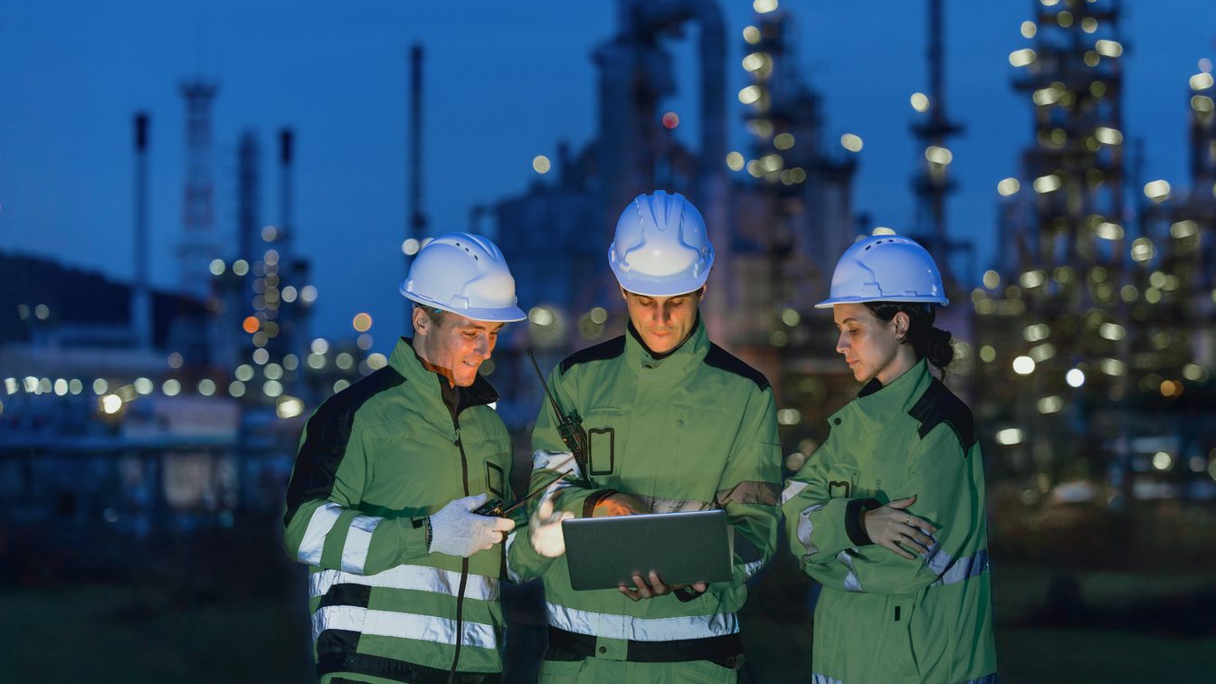 Equipo de ingenieros con cascos revisando una tableta en planta